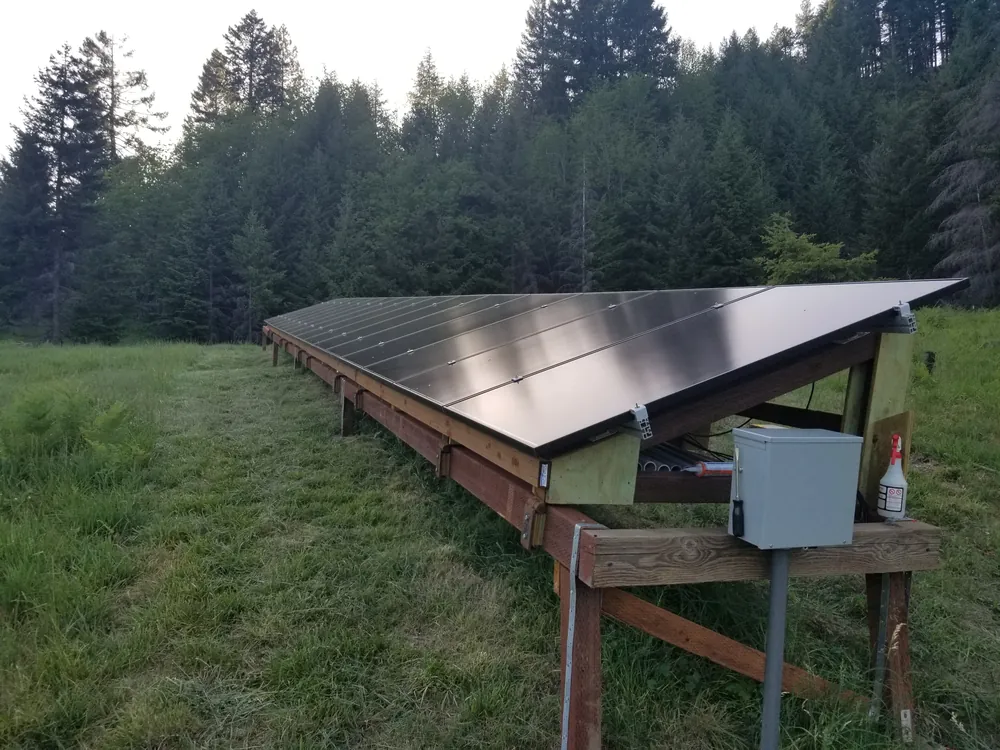 Large ground-mount solar array on a wood rack frame at an off-grid property